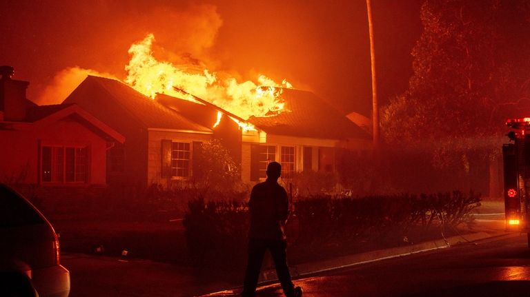 A firefighter walks toward a burning structure as the Eaton...