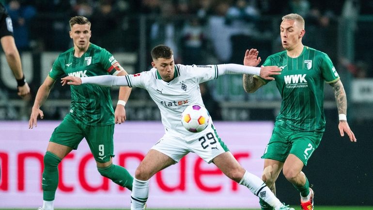 Gladbach's Joe Scally is challenged by Augsburg's Phillip Tietz, right,...