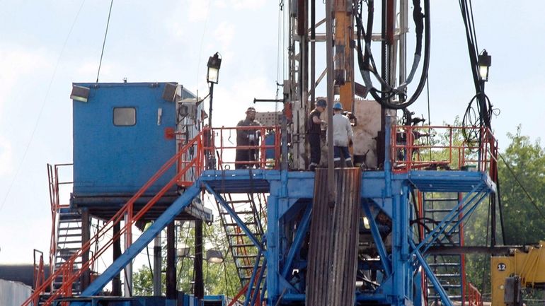 A crew works on a gas drilling rig at a...